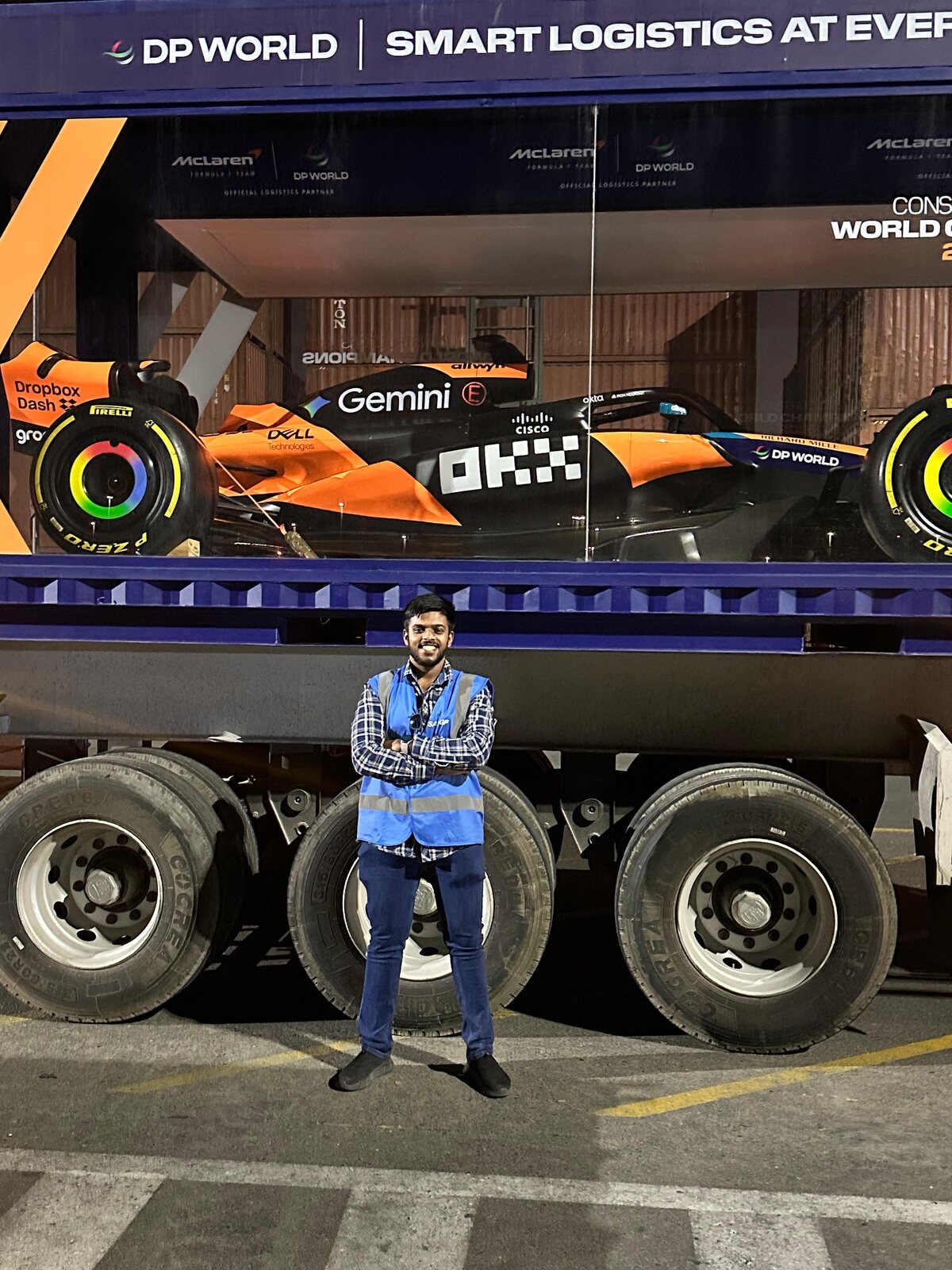 Kenny Colaco in DP World hi-vis in front of the McLaren F1 show car on a transporter